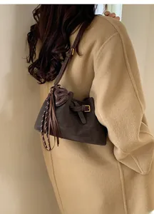 Détail du sac bandoulière en cuir marron avec gland et charm éléphant sur modèle