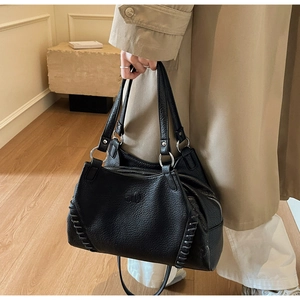 Detail of lychee textured black motorcycle bag with silver rivets and hand-stitched seams