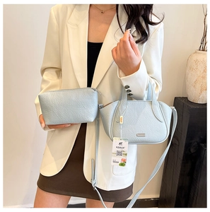 Detail der hellblauen Tasche mit Lychee-Struktur, Metall-Logo und passender Clutch