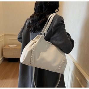 Close-up of cream lychee texture leather shoulder bag with hand-woven stitching detail