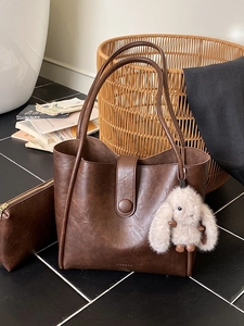Retro brown leather tote bag set with matching pouch and plush bunny charm on marble floor
