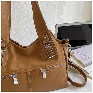 Detail of brown tote bag with metal zippers and matte leather texture on white background