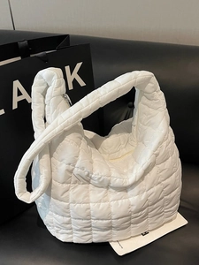 White quilted bubble puffer crossbody bag with large capacity and soft strap on a sofa