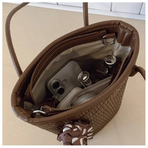 Detail view of large woven tote interior with zipper pocket, silk scarf, and daily items