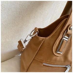 Detail of brown leather tote featuring reinforced stitching and silver metal hardware