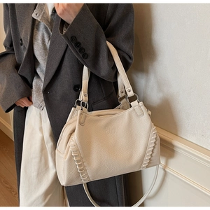 Detail of lychee pattern leather tote bag with thick woven stitching and long strap