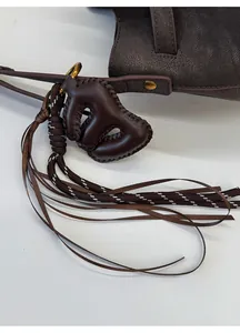 Détail d'un charm de sac en cuir marron foncé en forme de cheval avec couture main
