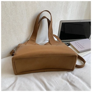 Detail view of large brown retro tote bag with dual handles and adjustable shoulder strap