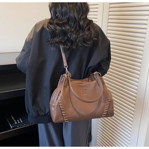 Detail view of brown leather tote bag with vintage stitching and embossed logo