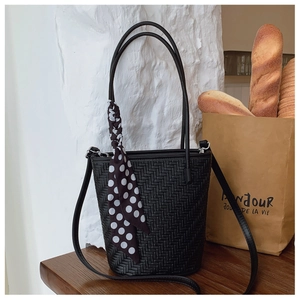 Detail of black woven bucket bag with polka dot scarf and adjustable crossbody strap