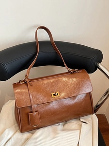 Vintage brown leather tote bag with gold metal buckle on a designer chair