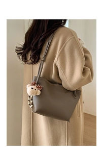 Détail du sac cabas en cuir marron argile avec breloque ours sur un manteau