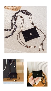 Detail of black suede mini crossbody bag with bead accents and silk scarf decoration