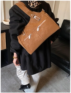 Close-up of brown vintage tote bag featuring multiple functional zipper pockets and buckles