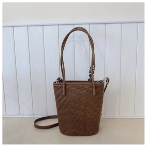 Detail of dark brown woven leather bucket bag featuring a decorative polka dot scarf