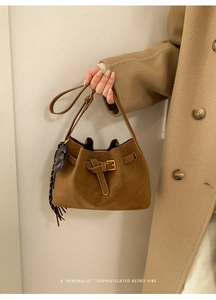 Détail du sac à main en daim marron avec sangle décorative et breloque cheval en cuir