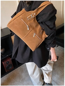 Detail of caramel brown matte leather shoulder bag featuring three silver front zippers
