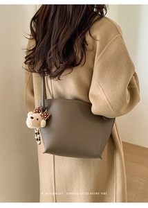 Détail du sac en cuir marron foncé avec texture grainée et pendentif ours mignon