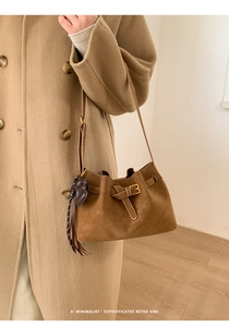 Détail du sac rétro en daim marron avec pendentif en cœur et fine bandoulière en cuir