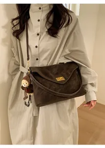 Detail of dark brown retro shoulder bag in faux suede with a cute bear charm on model