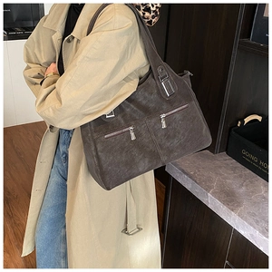 Detail of dark brown retro tote bag with dual front zippers and matte leather texture