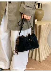 Détail d'un sac à main en daim noir avec boucle vintage et pompon en cuir élégant
