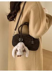 Detail of dark brown suede Boston bag with a cute plush bunny charm on long handle