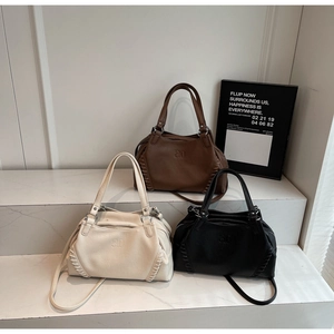 Detailed view of three lychee grain leather tote bags with woven edges in various colors