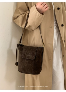 Détail d'un sac cabas en daim marron foncé avec rabat à logo et finitions dorées