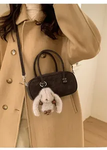 Brown Boston bag with matte finish and plush bunny pendant shown in a lifestyle setting