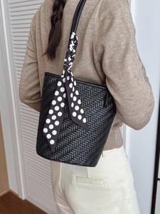 Large black woven shoulder bag with polka dot silk scarf detail shown on a model