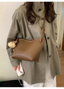 Vue latérale du sac fourre-tout en cuir marron grainé avec breloque d'ours peluche