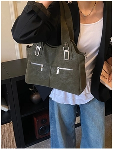 Detailed view of olive green tote bag with silver zippers and wide shoulder strap