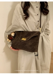 Detail of dark brown retro crossbody bag featuring golden turn-lock and plush bear charm