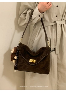 Detail of retro coffee brown shoulder bag with gold metal lock and bear charm accessory