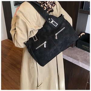 Close-up of black matte tote bag featuring dual silver zippers and a wide shoulder strap