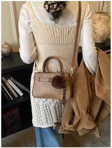 Modern brown woven texture bucket bag with plush charm shown in a crossbody style