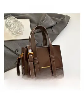 Detailed view of dark brown glossy leather shoulder bag with decorative buckle straps