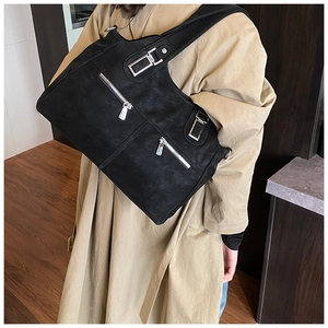 Side view of large matte black shoulder bag with silver zippers and wide straps