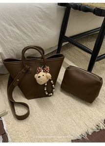 Détail du sac seau rétro en cuir litchi marron avec une breloque d'ours en peluche
