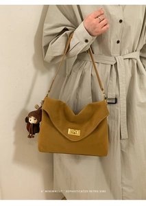 Detail of vintage yellow suede shoulder bag featuring gold twist lock and bear charm