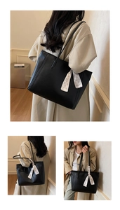 Detail of a black leather tote bag featuring a floral silk scarf tied to the slim shoulder strap