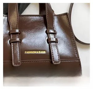 Detail of brown faux leather tote bag with gold lettering and precise stitching craft