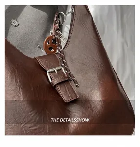 Close-up of dark brown underarm bag featuring lychee texture and metal buckle detail