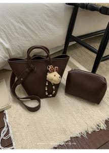 Sac seau en cuir grainé marron foncé avec charme de chiot sur un tapis moelleux