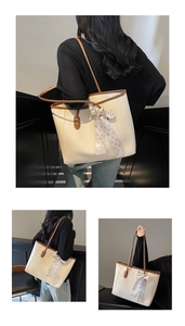 Detail of off-white tote bag with brown trim and elegant patterned scarf on handle