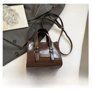 Detail of vintage brown leather tote bag with gold lettering and adjustable strap