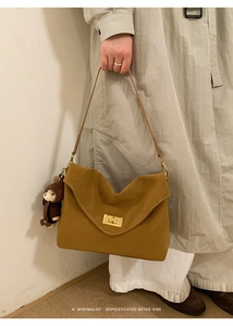 Detail of retro mustard yellow shoulder bag with gold twist lock and a cute teddy bear charm