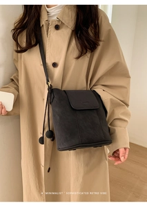 Détail du sac seau noir minimaliste en cuir avec breloque décorative en forme de boule