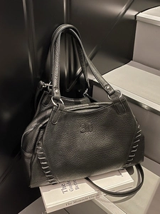 Chic black lychee grain motorcycle bag with woven side details on white book stand